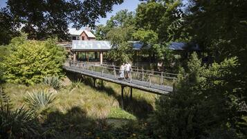 A wooden bridge over a pond with a gazebo and a building in the background.