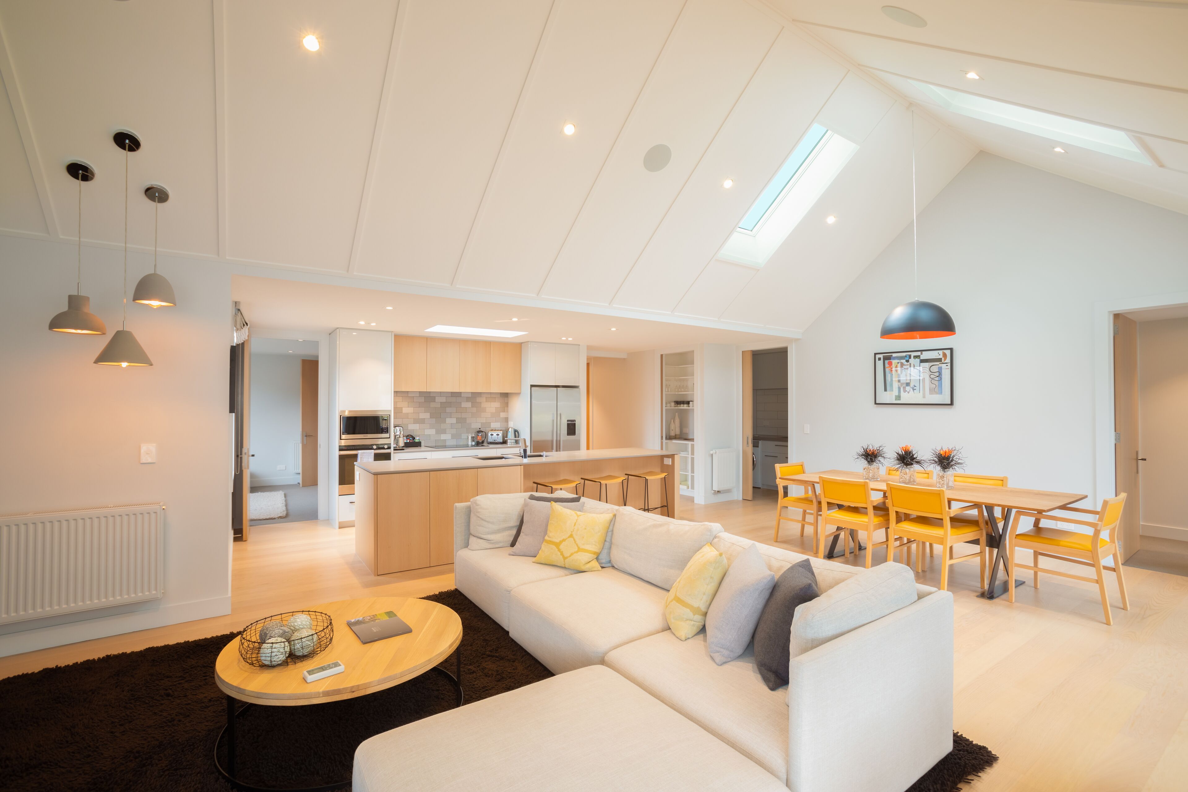A modern living room with a sofa, coffee table, and dining area.