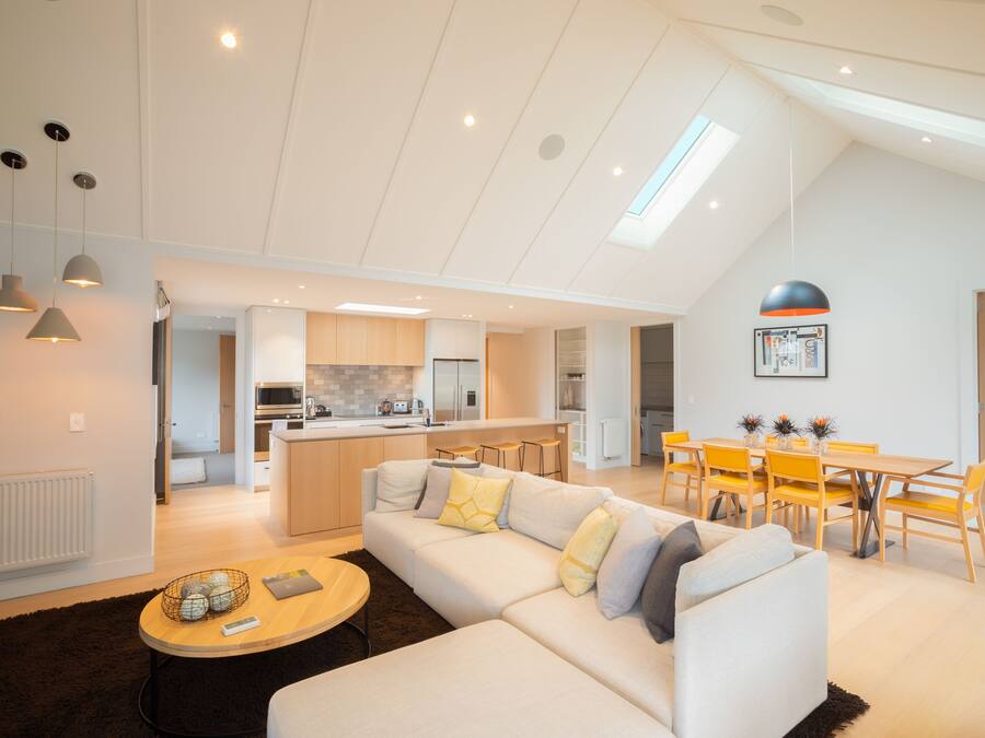 A modern living room with a sofa, coffee table, and dining area.
