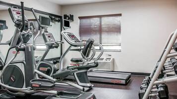 A gym with treadmills, elliptical machines, and a weight bench area.