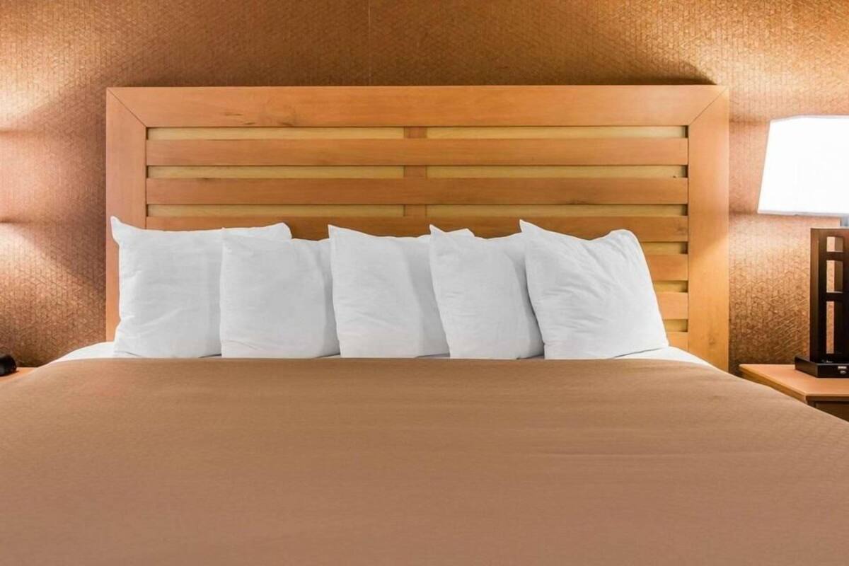 A bed with a wooden headboard, white pillows, and a brown bedspread.