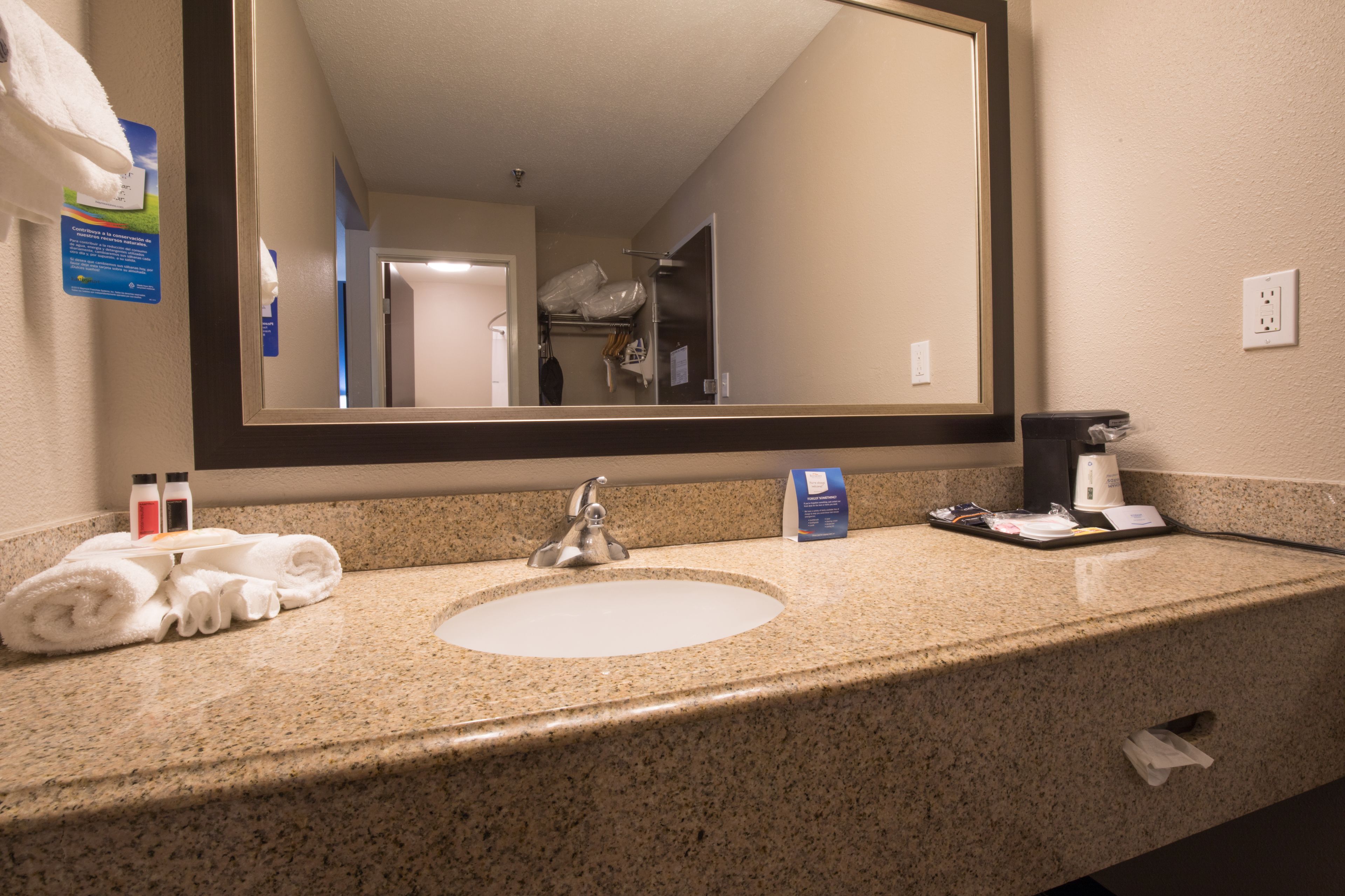 A hotel bathroom with a sink, mirror, and toiletries.
