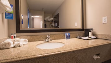 A hotel bathroom with a sink, mirror, and toiletries.