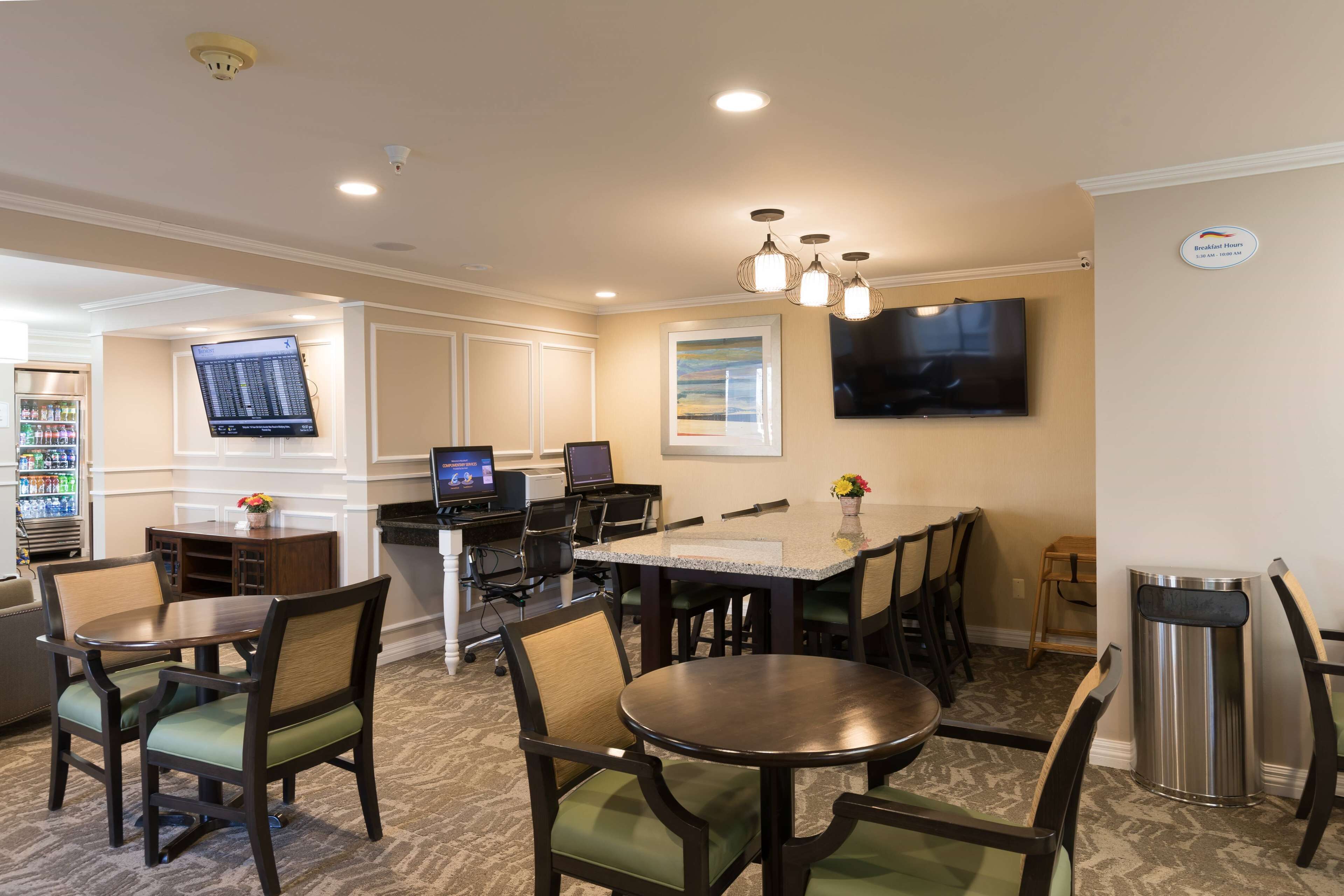 A hotel room with a dining area, a TV mounted on the wall, and a trash can.