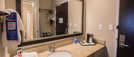 A hotel bathroom with a sink, mirror, towel rack, and toiletries.