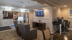 A hotel lobby with a reception desk, seating area, and a television screen. - Baymont by Wyndham Detroit Airport/Romulus (Romulus)