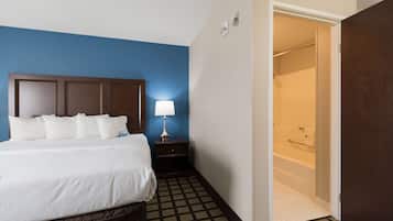 Een hotelkamer met een bed, een nachtkastje met een lamp, een douchegedeelte en een vloer met een patroon.