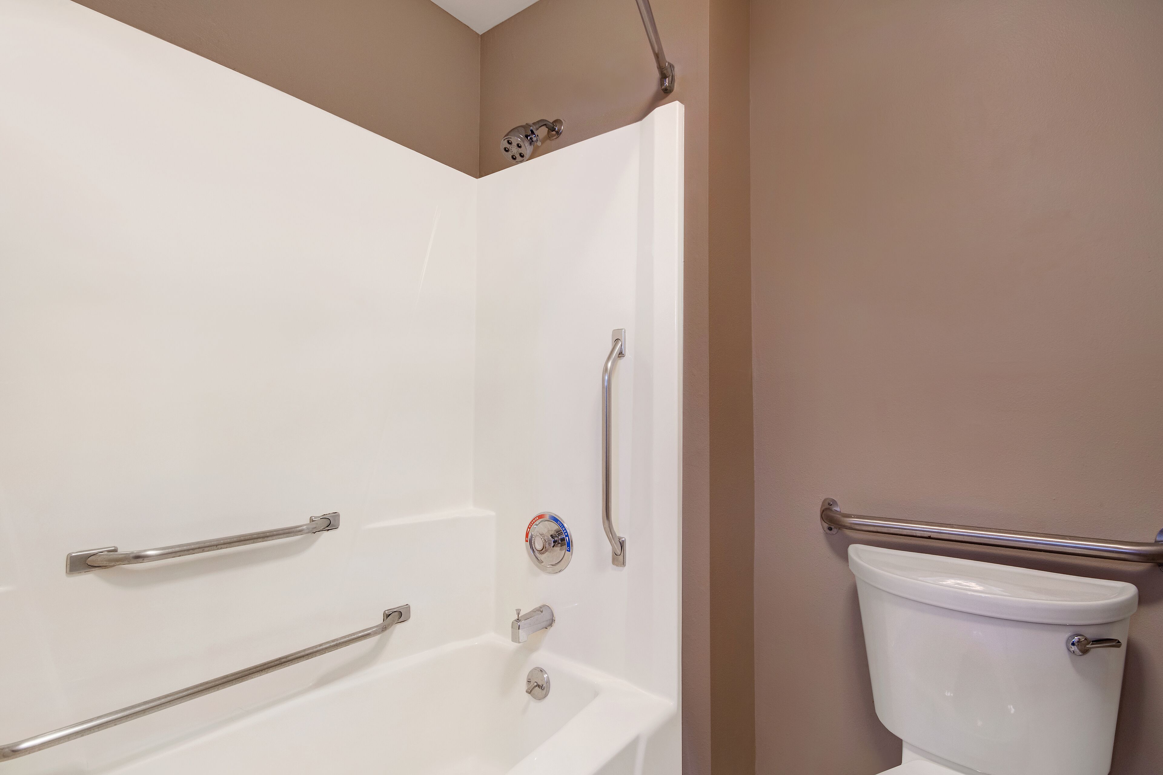 A bathroom with a white bathtub, a toilet, and a shower area.
