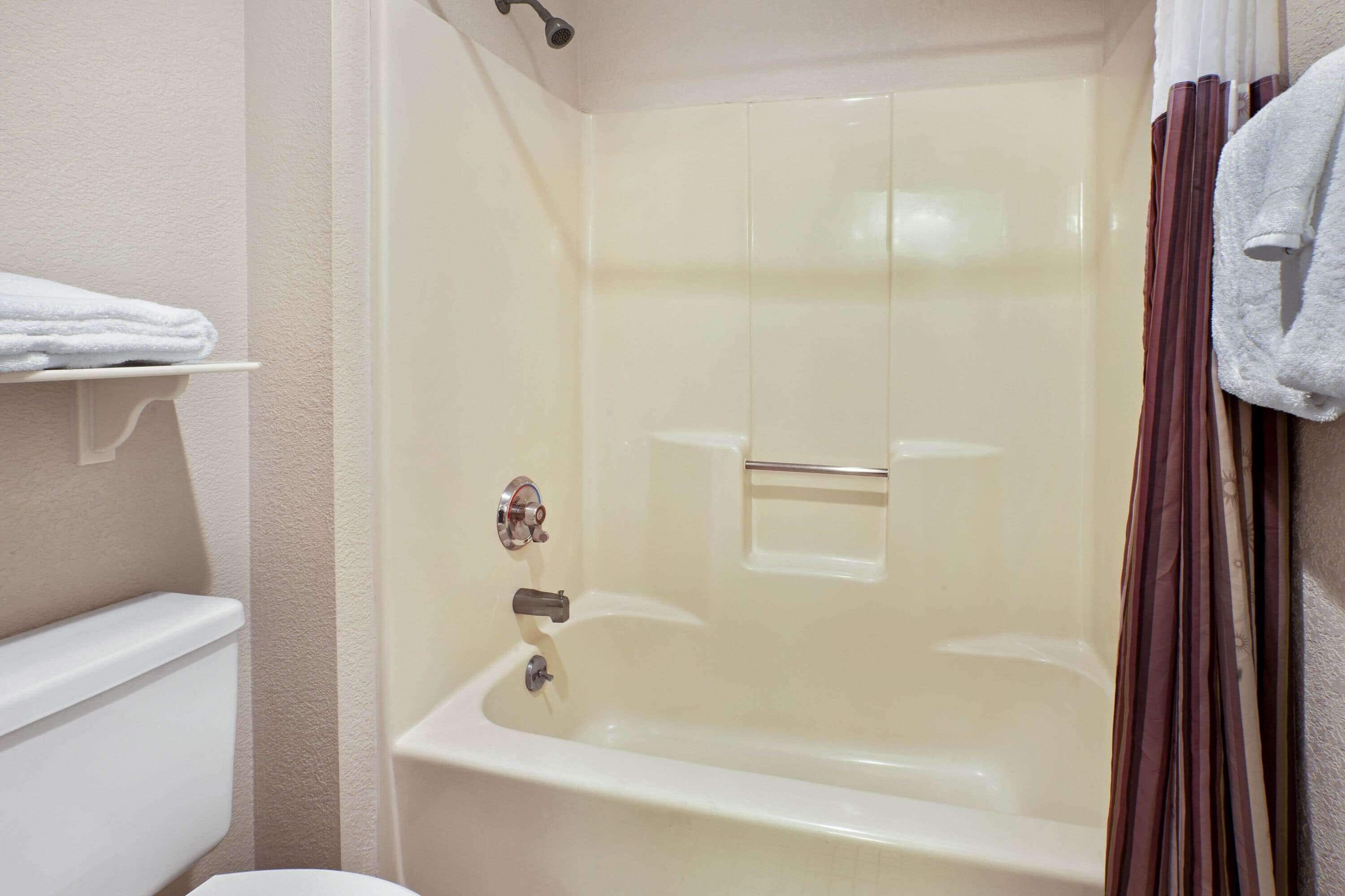 Un bagno con una vasca, un water e uno scaffale con asciugamani.