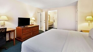 Une chambre d’hôtel équipée d’un lit, d’un bureau, d’une télévision et d’une commode.