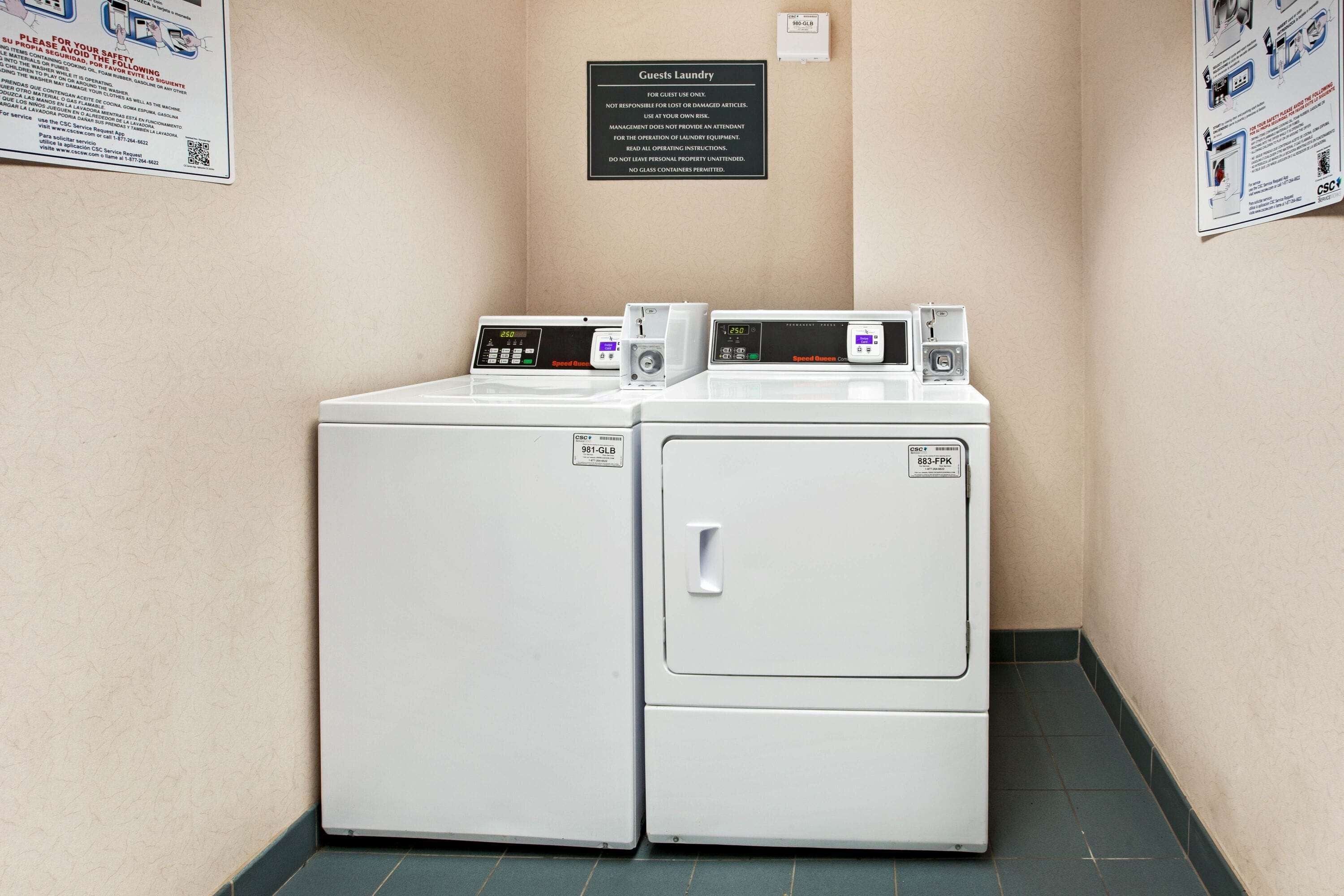 A laundry area with two front-loading washing machines, a sign above them, and a wall-mounted outlet.