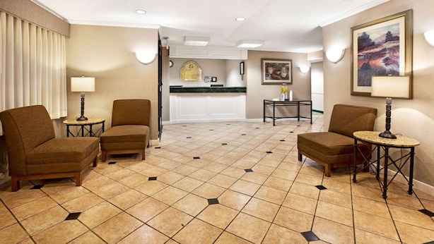 Un hall d’hôtel avec un comptoir d’accueil, deux fauteuils, une petite table et un tableau accroché au mur.