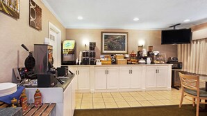 Une cuisine d’hôtel équipée d’un coin café, d’un téléviseur fixé au mur et d’un espace repas avec une chaise.