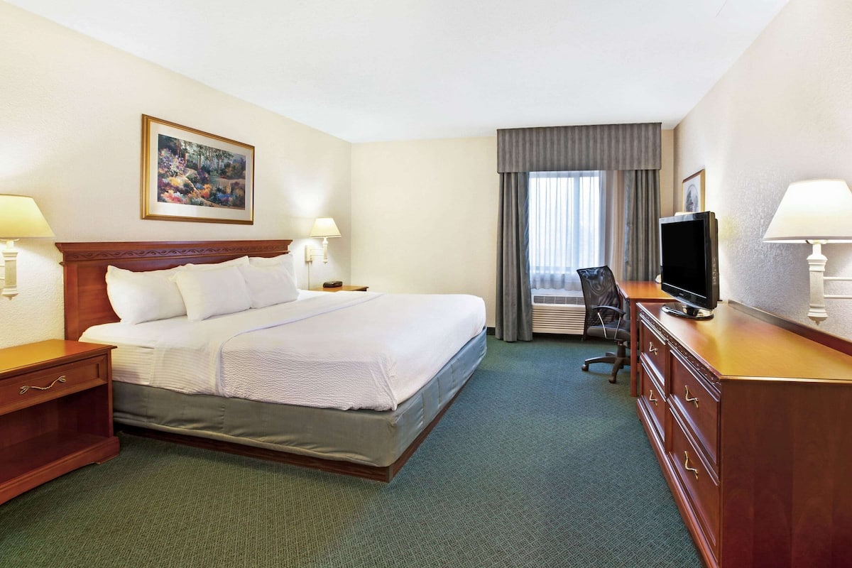 A hotel room with a large bed, a desk with a computer, a TV, and a chair.