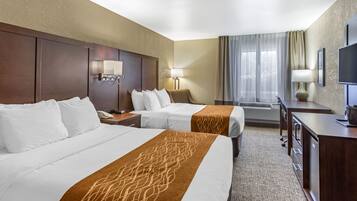 A hotel room with two beds, a desk, a chair, a TV, and a window with curtains.