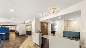 Een hotel receptie met een modern design, met een receptiebalie, een klok en een wand van steen.