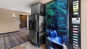 Hotelkamer met een koelkast, een waterdispenser en een automaat met drankjes.