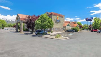 A Comfort Inn hotel with a mountain backdrop, a parking lot, and a clear sky.