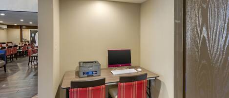 Habitación de hotel con escritorio, dos sillas, computadora e impresora.