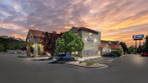 Een Comfort Inn hotel met een parkeerplaats, een berg op de achtergrond en een zonsondergang.