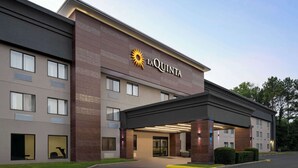 Hotel La Quinta con fachada moderna, entrada cubierta y estacionamiento.