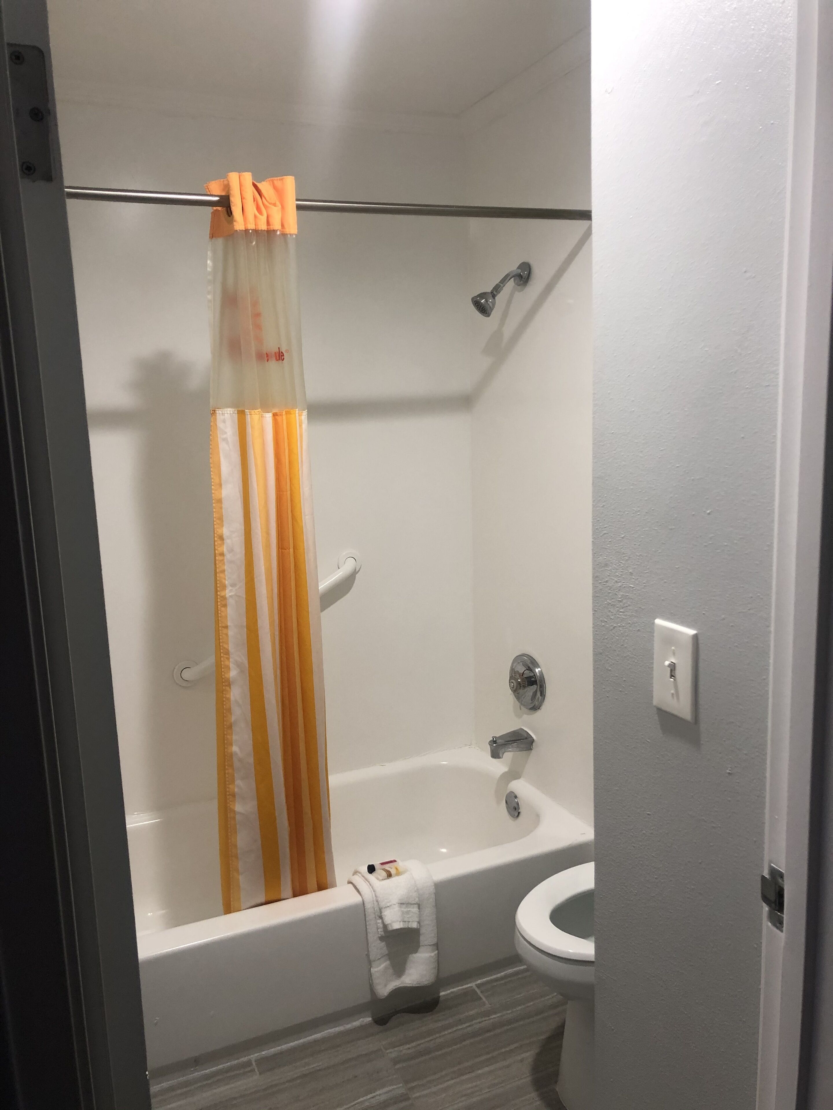 A bathroom with a bathtub, toilet, and shower curtain.