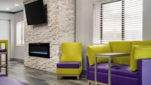 Un área de descanso moderna con pared de piedra, un televisor de pantalla plana y un conjunto de sofás.