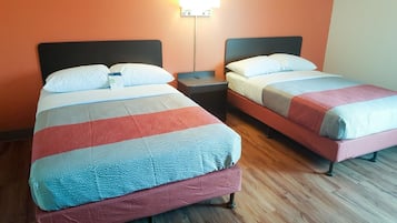 Two single beds with striped bedding, wooden flooring, and a nightstand between them.