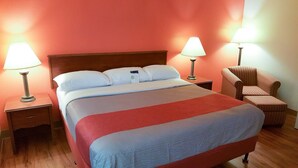 A hotel room with a large bed, two bedside lamps, a chair, and a nightstand. - Motel 6 Maryland Heights, MO (Maryland Heights)