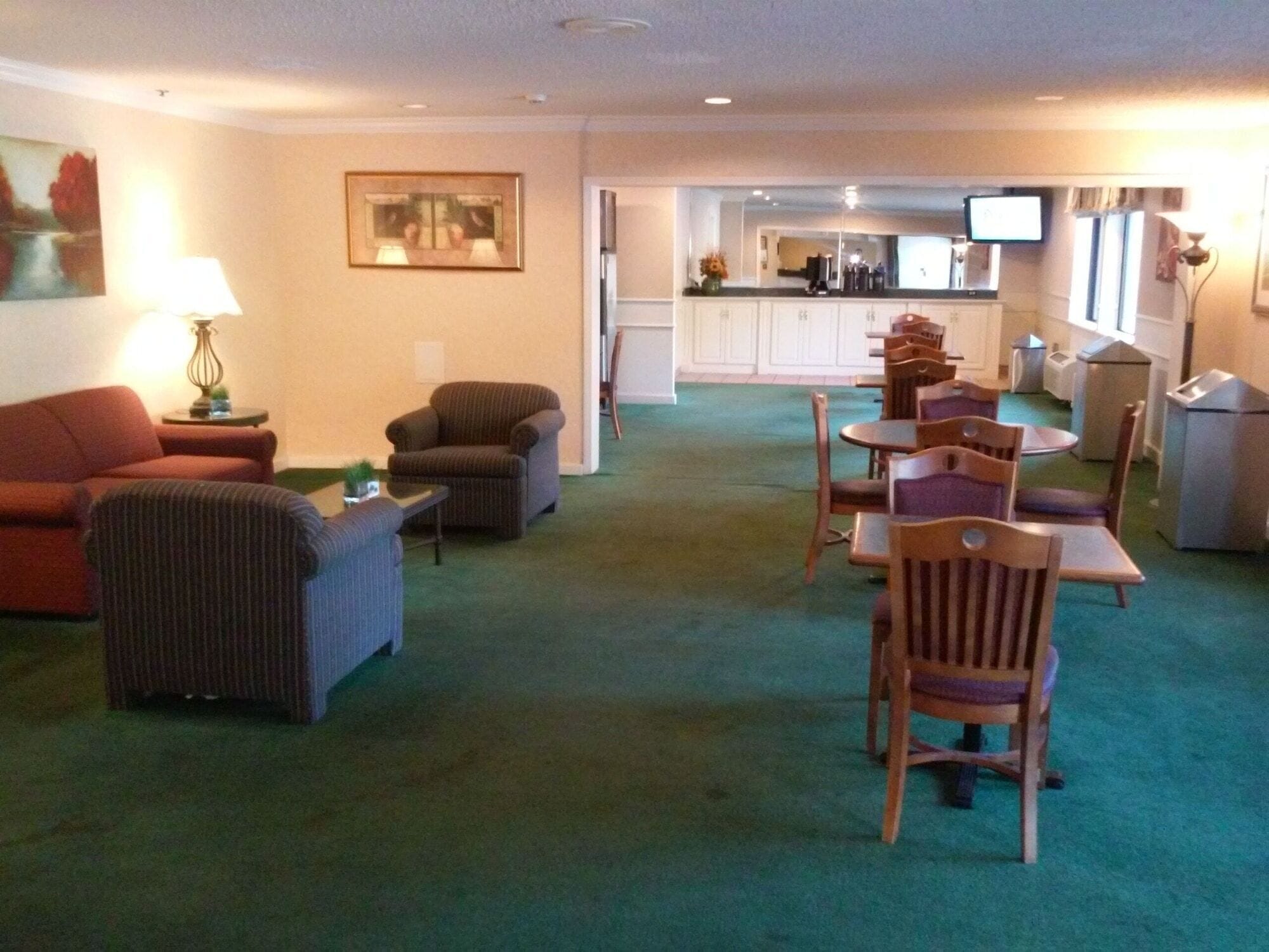 A living room with a sofa, armchair, and a dining area with chairs and a table.