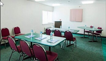 A conference room with tables and chairs, water bottles on tables, and a projector screen on the wall.