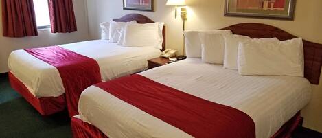 A hotel room with two beds, each with red and white bedding, a bedside lamp, and a framed picture on the wall.