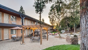 A hotel with a covered patio area featuring outdoor seating and a fire pit.