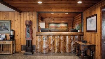 A rustic interior with wooden walls, a wooden ceiling, a bar area, and a painting on the wall.