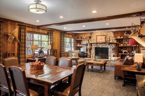 A rustic interior with wooden walls, a stone fireplace, and a deer head mounted on the wall.