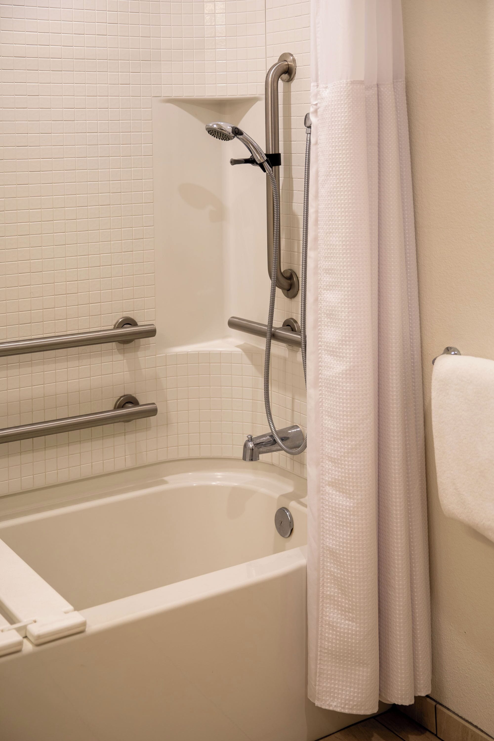 A bathroom with a bathtub, a shower with a handheld showerhead, and a towel rack.
