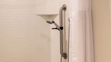 A bathroom with a bathtub, a shower with a handheld showerhead, and a towel rack.