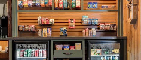 A snack bar with refrigerated beverage dispensers and shelves stocked with various snacks and beverages.