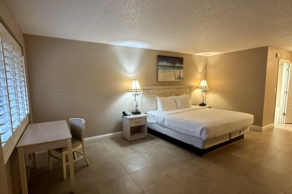 A bedroom with a bed, bedside tables, a chair, and a desk.