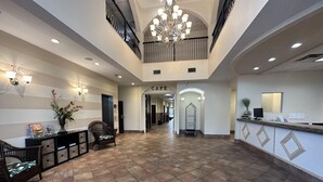 A spacious lobby with a reception desk, a chandelier, and a cafe sign.
