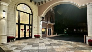 A spacious entrance with a tiled floor, large arched doorway, and potted plants.