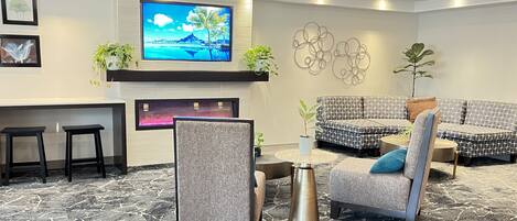 A modern lobby with a flat-screen TV, seating area, and a reception desk.