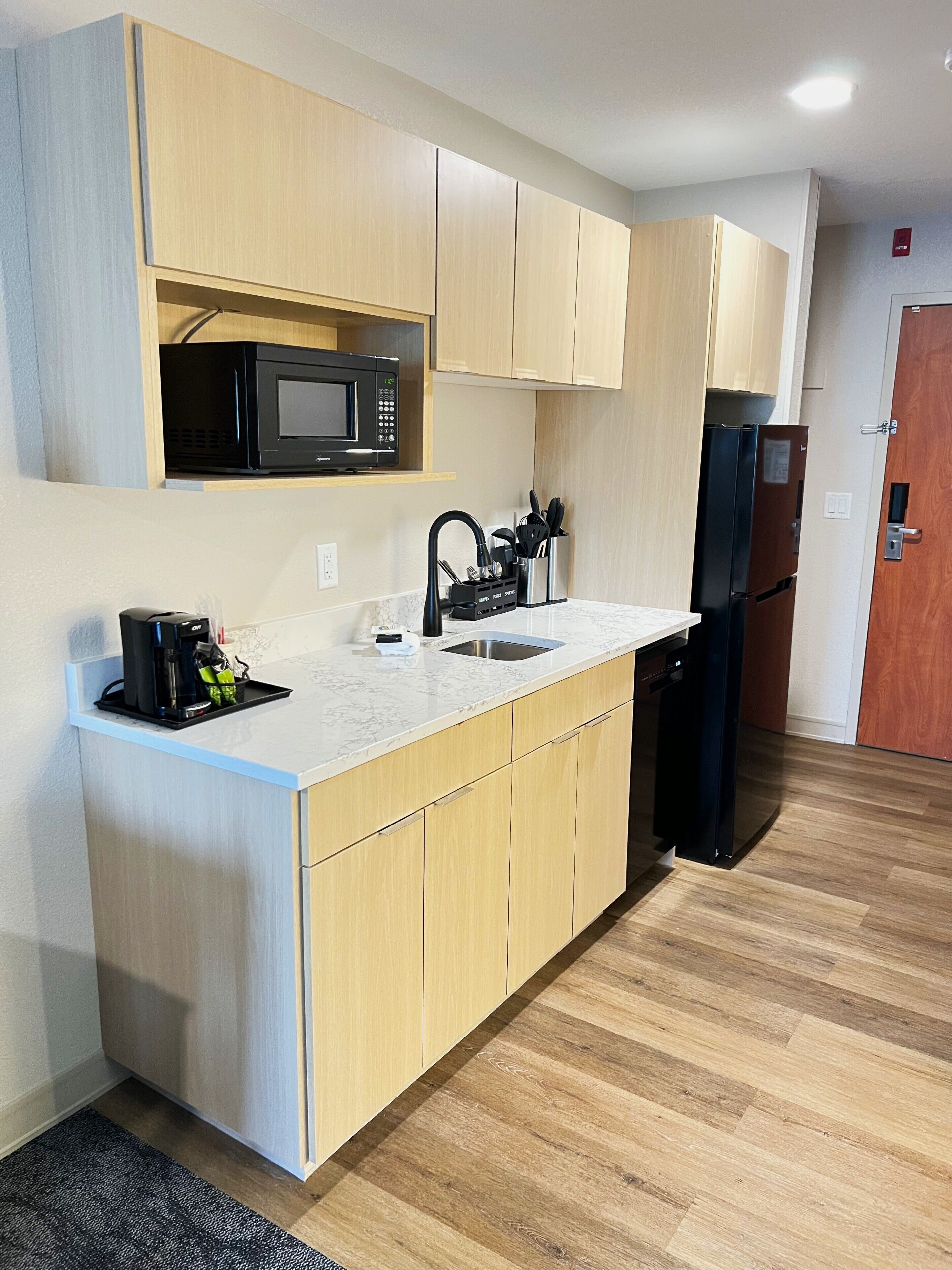 A compact kitchen with a microwave, sink, and refrigerator.