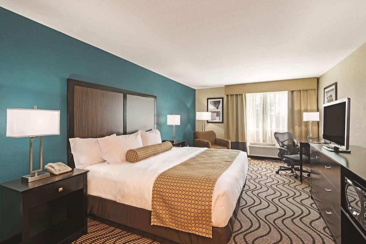 A hotel room with a bed, desk, chair, television, and a telephone.