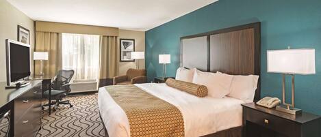 A hotel room with a bed, desk, chair, TV, and a phone.