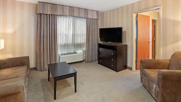 Habitación de hotel con sofá, televisión, una mesita y una puerta.