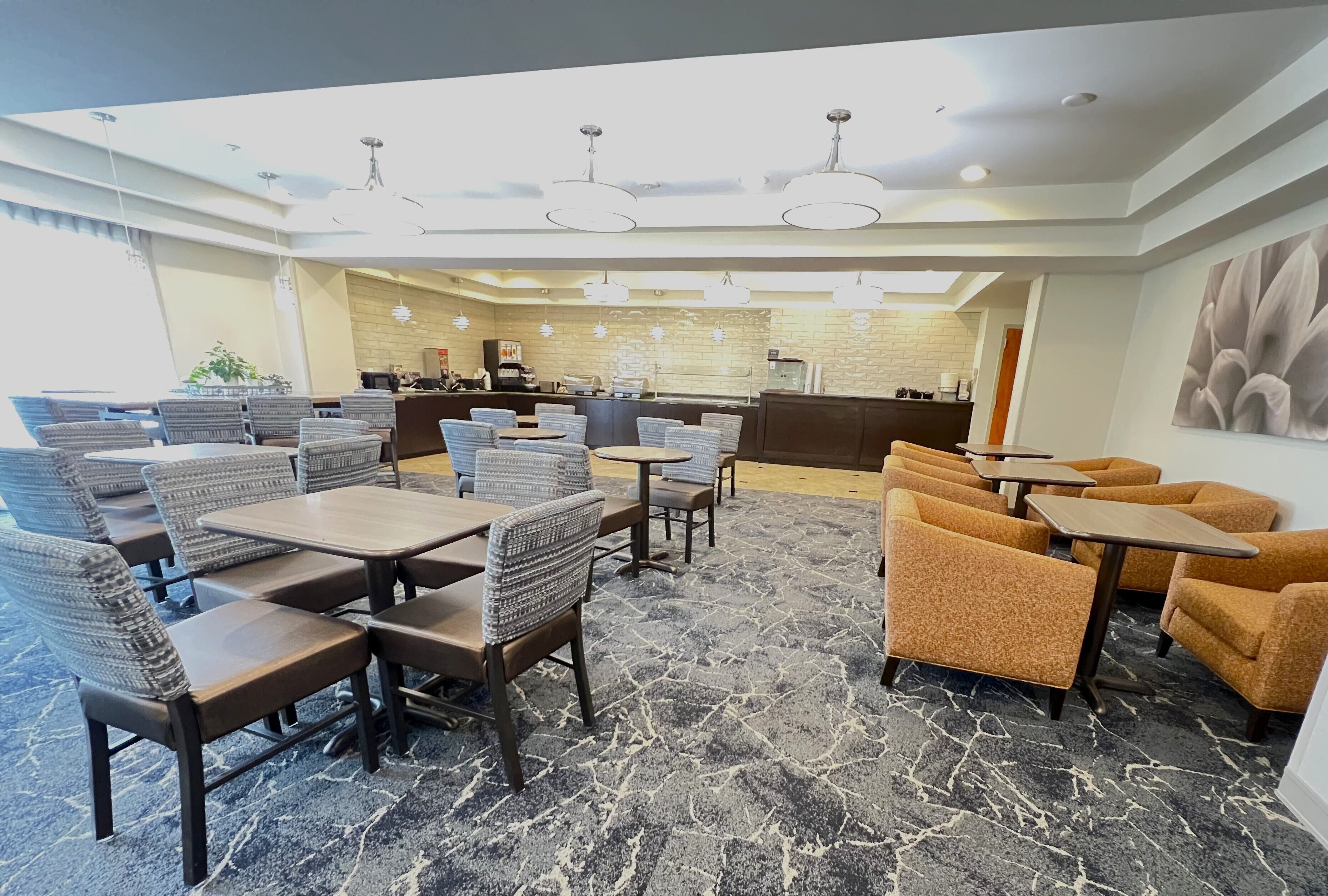 Un hall d’hôtel avec des espaces aménagés pour s’asseoir, un comptoir de réception et une cuisine en arrière-plan.