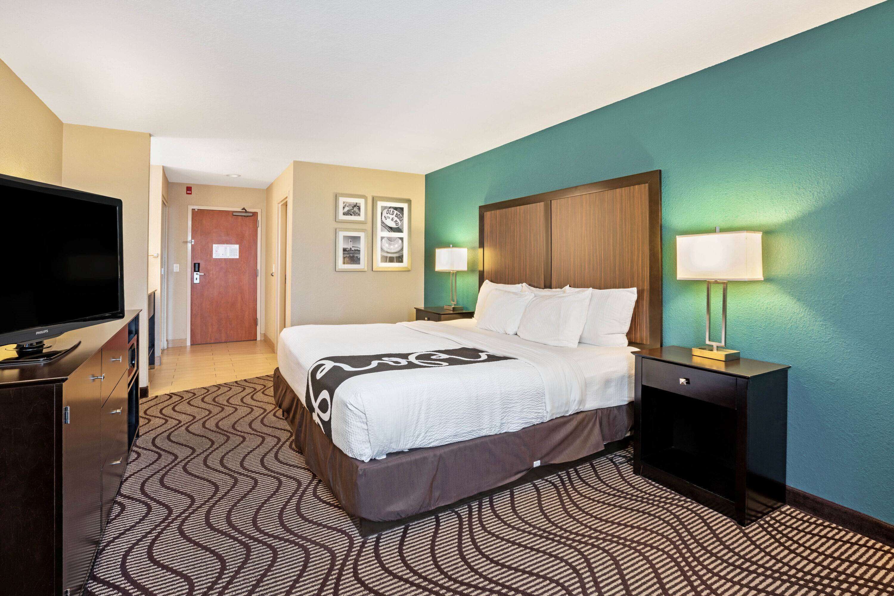 A hotel room with a bed, a TV, a desk, and a lamp.