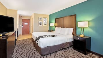 A hotel room with a bed, a TV, a desk, and a lamp.