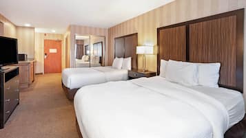 A hotel room with two beds, a television, a desk, and a mirror.